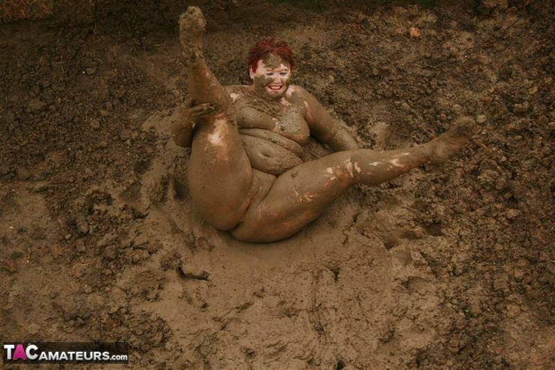 Older redhead Valgasmic Exposed rolls around in a mud pit while totally naked - #1