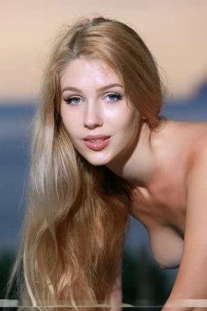 Beautiful blonde with long hair Xana D poses totally naked near the ocean on amateurlikes.com