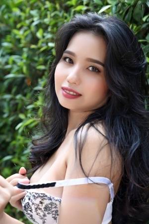 Beautiful Asian girl Norah gets totally naked next to a hedge in a garden on amateurlikes.com